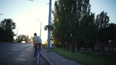 Genç çocuk boş yol gündoğumu yavaş hareket hızlı bir bisiklet sürme yerleştirmek