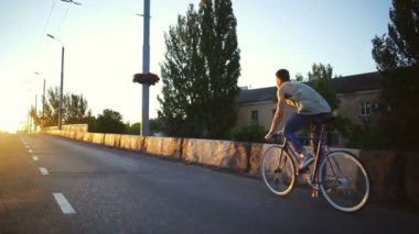 Genç çocuk hızlı hızlı boş yol gündoğumu yavaş hareket üzerinde bir bisiklet sürme yerleştirmek