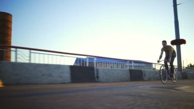 Genç yakışıklı çocuk boş yol gündoğumu yavaş hareket hızlı bir bisiklet sürme