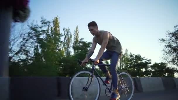 Jonge knappe man die een fiets op de lege straat zonsopgang slow motion — Stockvideo