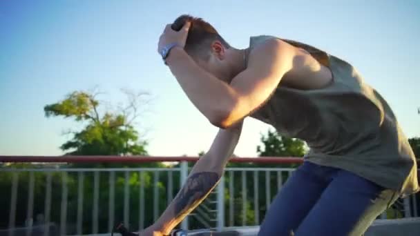 Fitter Mann mit Tätowierung beim Fahrradfahren und Berührung der Haare Sonnenaufgang Zeitlupe schnell — Stockvideo