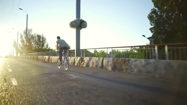 Νεαρό αγόρι ιππασίας ένα ποδήλατο για το άδειο ηλιόλουστο δρόμο sunrise αργή κίνηση ταχεία — Αρχείο Βίντεο