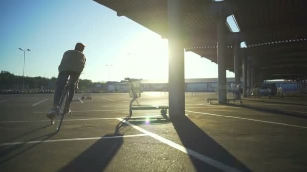 Boy ridning cykel tom bil parkering kretsande pelare sunrise slowmotion snabb — Stockvideo