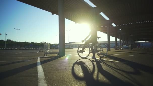 Jongen silhouet verblijf met de fiets op de lege parkeren sundown slowmotion snelle — Stockvideo