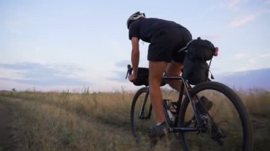 Güçlü bisikletçi siyah takım elbise binmek bisiklet valley road gündoğumu yavaş hareket hızlı