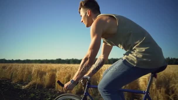 Starker junger Mann mit Fahrrad in der Nähe von Weizenfeld Sonnenuntergang Zeitlupe schnell — Stockvideo