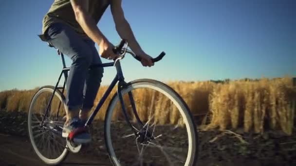 Stark ung pojke ridning cykel nära vete fält sundown slowmotion snabb — Stockvideo