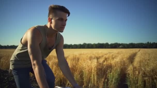 Sterke jongen fietsten in de buurt van tarwe veld sundown slowmotion snelle — Stockvideo