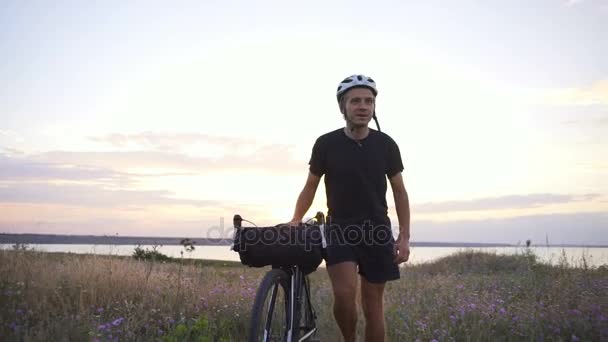 Ciclista a pie bicicleta despegar casco flor campo amanecer playa cámara lenta rápido — Vídeos de Stock