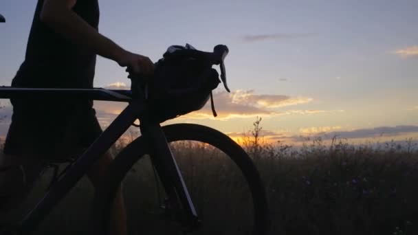 Bliska spaceru człowiek z rowerem w kwiat pole sundown nadmorskiej zwolnionym tempie szybkim — Wideo stockowe