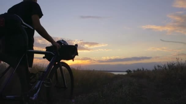 Homme marche avec vélo dans le champ de fleurs coucher de soleil bord de mer ralenti rapide — Video