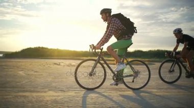 Bisiklet sürmek birlikte kask kum Sahil gün batımından yavaş hareket hızlı