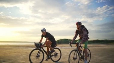 Genç bisikletçiler rides birlikte kum sahil kask şafak yavaş hareket hızlı