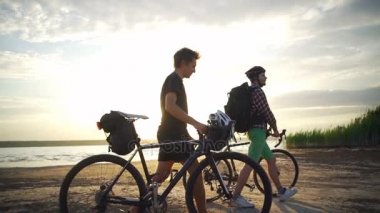 İki bisikletçiler Bisiklet Sahil gün batımından yavaş hareket hızlı ile deniz kenarında yürüyüş