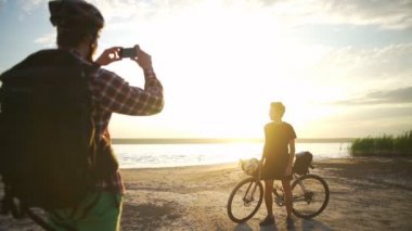 bisikletçiler başka bir bisikletçi smartphone deniz şafak ağır çekim fotoğraf hızlı olun