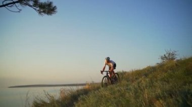 Genç bisikletçi binmek bisiklet sahil Okyanusu günbatımı kask hızlı yavaş hareket uygun