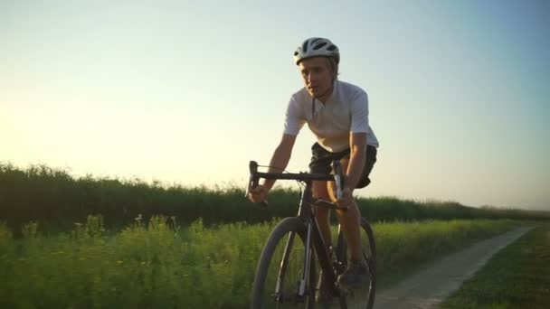 Vältränad Cyklist rida cykel tom väg gröna fältet sunset snabba slowmotion — Stockvideo