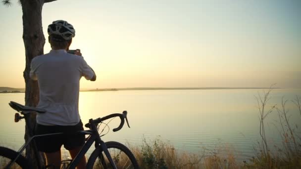 Bicyclist fica costa vista para o mar com bicicleta fazer capacete foto rápida câmera lenta — Vídeo de Stock