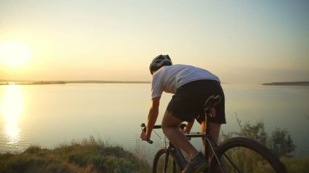 Велосипедист едет вниз по побережью горы шлем восхода солнца быстрое замедленное движение — стоковое видео
