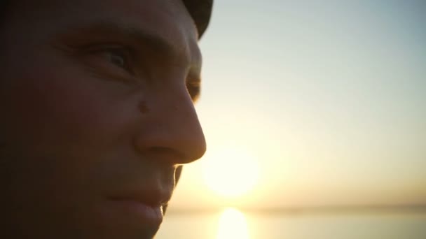 Gros plan homme en casque avec taupe sur le nez vue sur la mer coucher de soleil rapide ralenti — Video