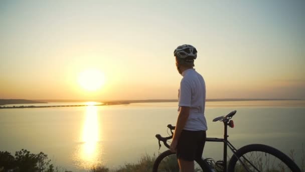 Joven ciclista con bicicleta disfruta de la puesta del sol costa vista rara apid cámara lenta — Vídeos de Stock