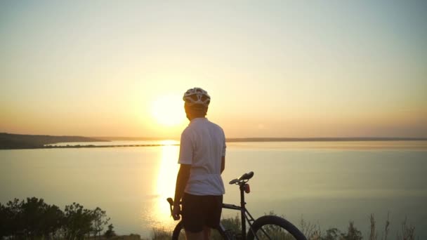 Ciclista stands com bicicleta desfrutar de pôr do sol costa rara vista apid câmera lenta — Vídeo de Stock
