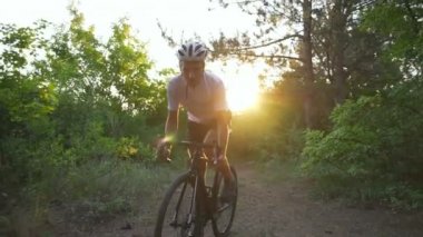 Yakışıklı bisikletçi binmek bisiklet orman yol gündoğumu kask hızlı yavaş hareket