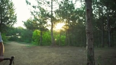 Yakışıklı bisikletçi kalın ormanda Bisiklet günbatımı kask hızlı yavaş hareket ile