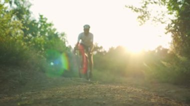 Bisikletçi binmek güneşli orman yol gündoğumu kask hızlı yavaş hareket üzerinde