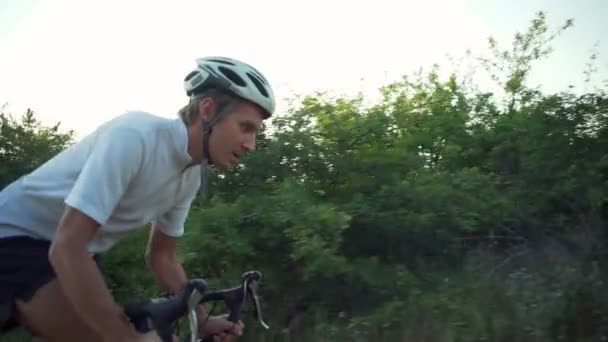 年轻车手骑自行车阳光森林路日出头盔快速慢动作 — 图库视频影像