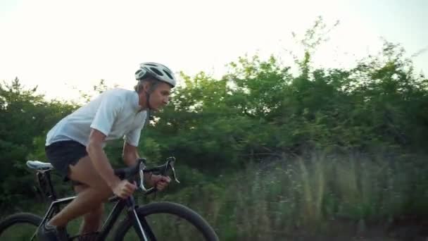 Schöner Radfahrer fahren Fahrrad sonnig Waldstraße Morgendämmerung Helm schnelle Zeitlupe — Stockvideo