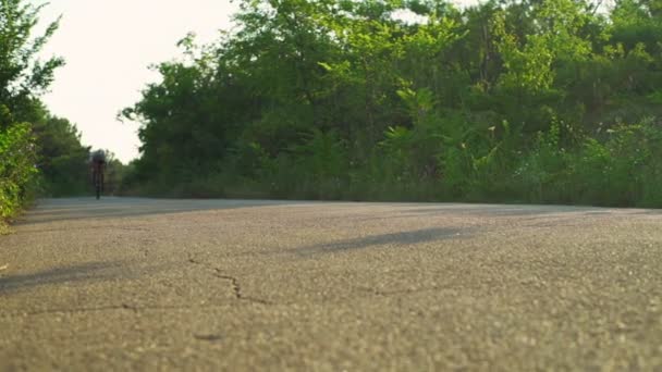 骑自行车的人骑在森林日出头盔快速慢动作阳光沥青路面 — 图库视频影像