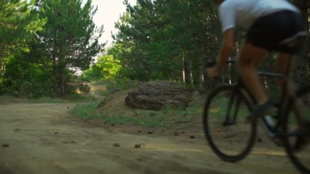Kerékpáros lovagolni kerékpár kanyargós erdei utat dawn sisak hátsó nézet gyors lassú mozgás — Stock videók