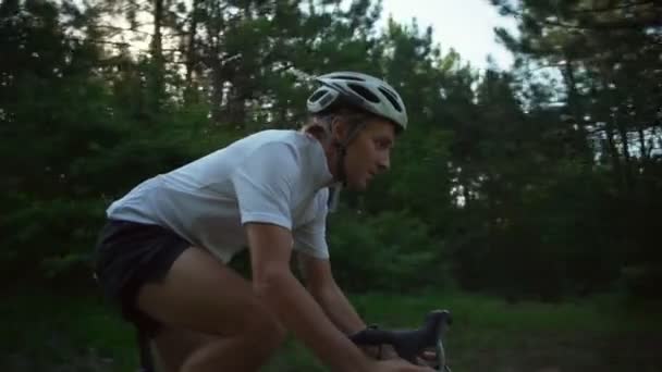 Jovem ciclista passeio de bicicleta sol denso floresta caminho madrugada capacete rápido câmera lenta — Vídeo de Stock