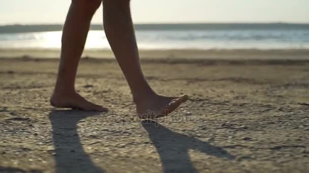 Fechar o homem andando praia de areia descalço à beira-mar nascer do sol rápido câmera lenta — Vídeo de Stock