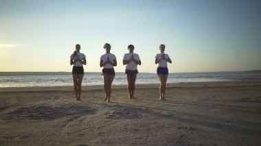 Bir grup insan yoga kartal poz Sahil gün batımından hızlı yavaş hareket yapıyor