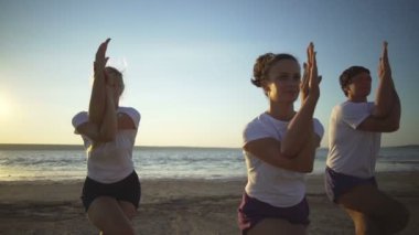 Bir grup insan pratik yoga kartal poz Sahil gün batımından hızlı yavaş hareket