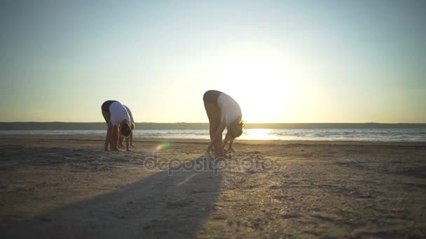Groupe de personnes pratiquant le yoga pose bord de mer coucher de soleil rapide ralenti — Video