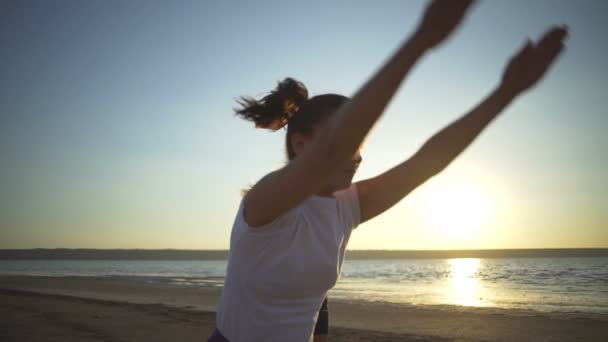 Dos jóvenes haciendo yoga posa namaste puesta de sol junto al mar rápida cámara lenta — Vídeos de Stock