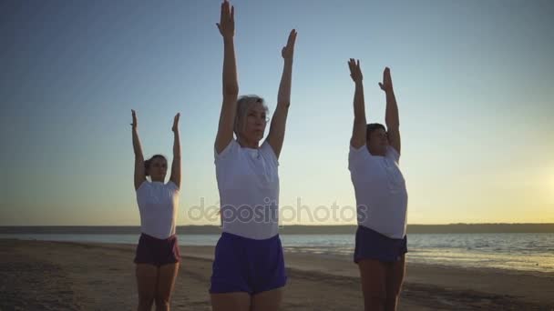 Grupo de personas practican yoga posan namaste playa amanecer rápido cámara lenta — Vídeos de Stock