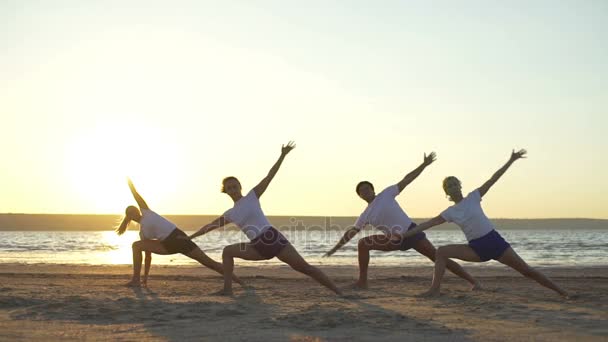 Clase de yoga practicando asanas al amanecer a orillas del mar en cámara lenta rápida — Vídeos de Stock