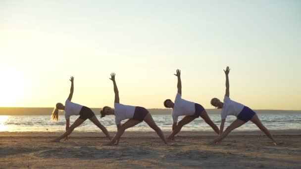 Groep van jonge mensen die het beoefenen van yoga aan zee zonsopgang snelle langzame motie — Stockvideo