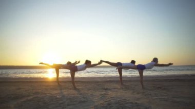 Yoga savaşçı grup insanlar sahil gündoğumu hızlı yavaş poz