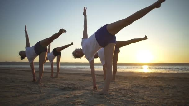 Группа людей практикующих йогу на берегу моря восход солнца быстрое замедленное движение — стоковое видео