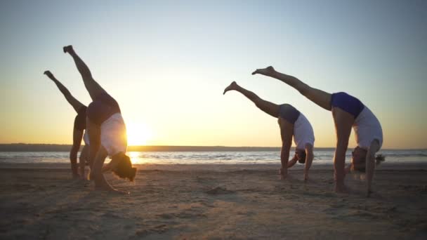 Groupe de personnes font yoga pose cohérence bord de mer lever du soleil rapide ralenti — Video