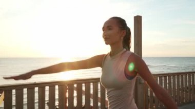 Esnek Kafkasyalı kız çatıda gün ışığında savaşçı yoga pozu veriyor.