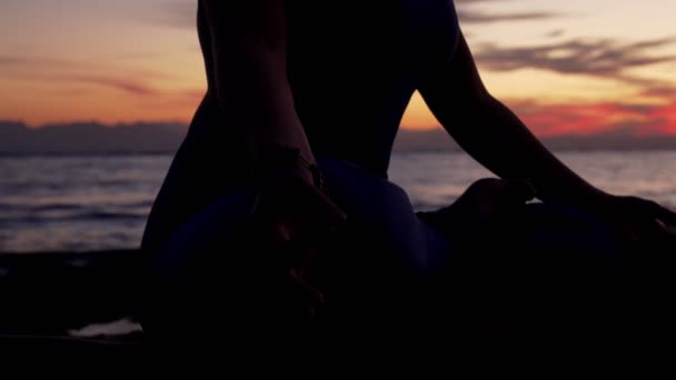 Nahaufnahme Silhouette Frau meditiert gegen das Meer bei buntem Sonnenuntergang — Stockvideo