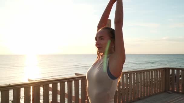 Lány gyakorló harcos jóga póz a tetőn a napsütésben. A kamera távolodik. — Stock videók