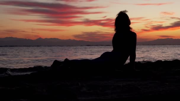 Silhouette donna medita contro il mare al tramonto colorato — Video Stock