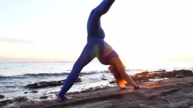 Kafkasyalı kız gün batımında deniz kıyısında camatkarasana yogası yapıyor.